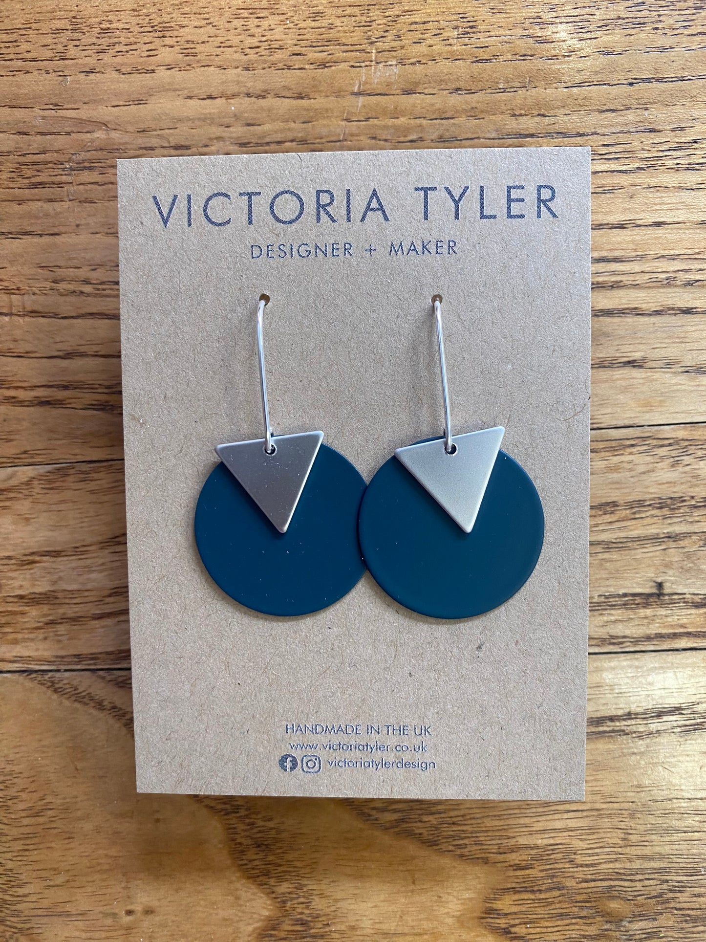 Slate Grey Circle Dangly Earrings with Silver Plate Triangles - 'Kiki'. On a black backing card which says 'Victoria Tyler, Designer + Maker