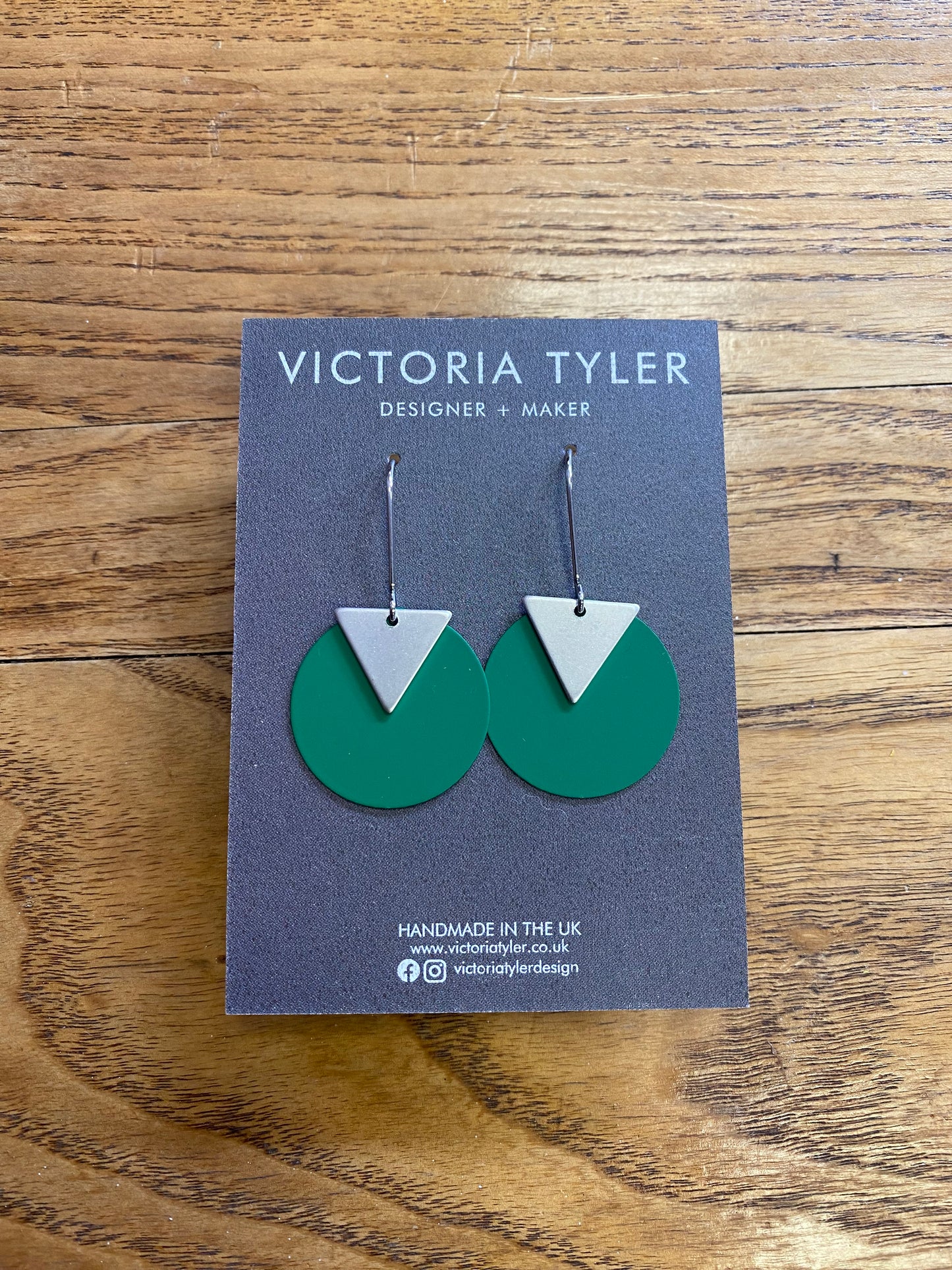 Green Circle Dangly Earrings with Silver Plate Triangles - 'Kiki'. On a black backing card which says 'Victoria Tyler, Designer + Maker